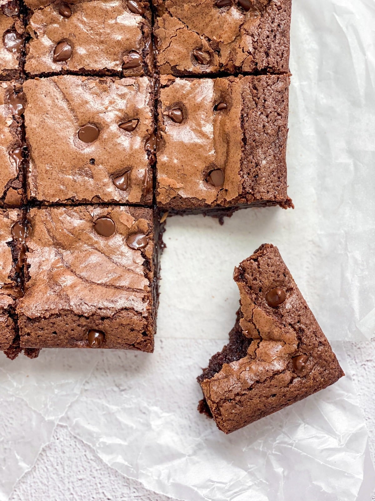 An overhead shot of double chocolate fudge brownies cut into squares with one with a bite taken out of it.