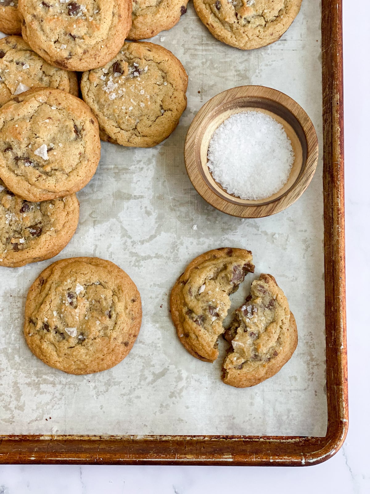 Baked chocolate chunk cookies with one split in half with some salt on the side.