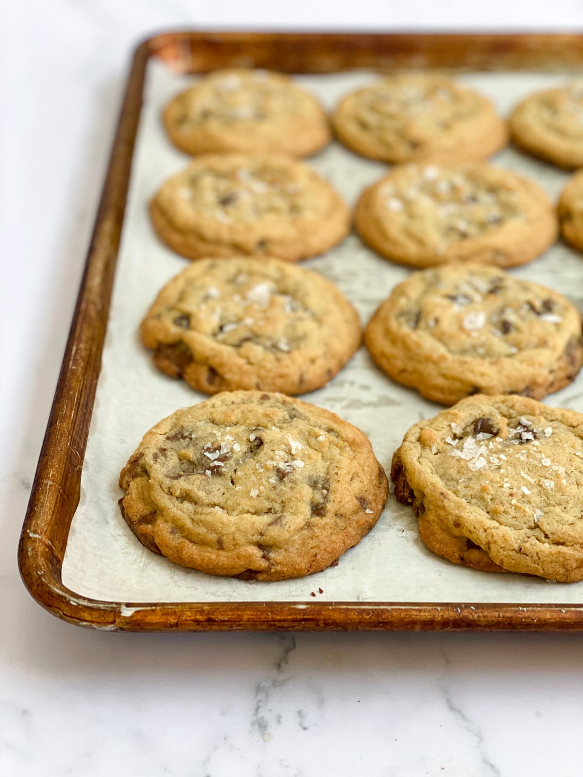 Baked salted chocolate chunk cookies on a baking sheet.