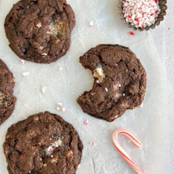 a peppermint hot chocolate cookie with a bite missing and a few peppermint candy pieces around.