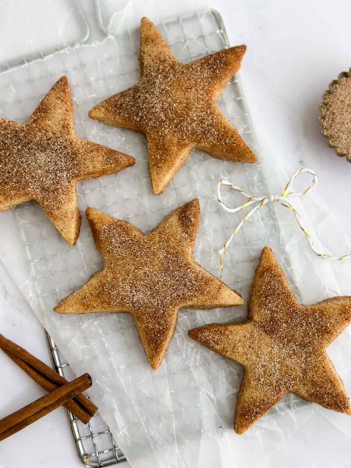 4 cinnamon shortbread cookies with a few cinnamon sticks to the side.