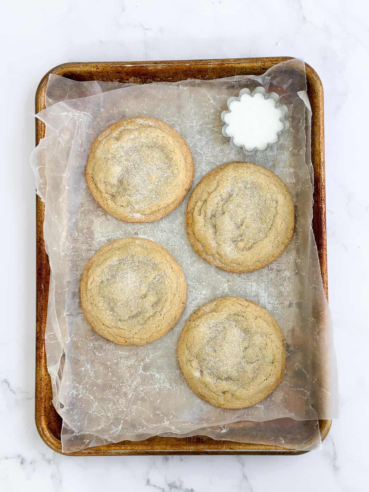 4 small batch sugar cookies on a baking sheet.