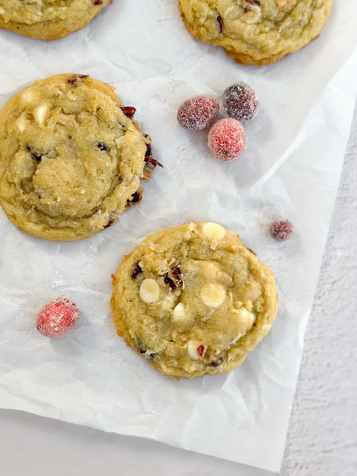 a close up of two white chocolate orange cranberry cookies.