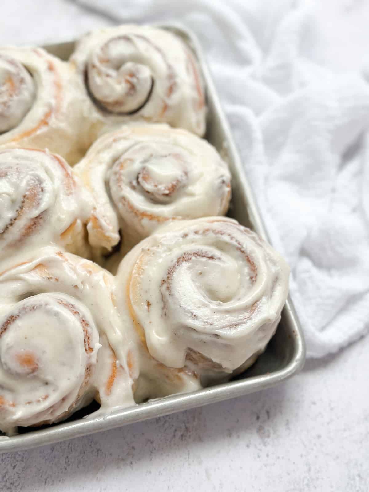 a side view of the small batch cinnamon rolls in the pan after frosting.