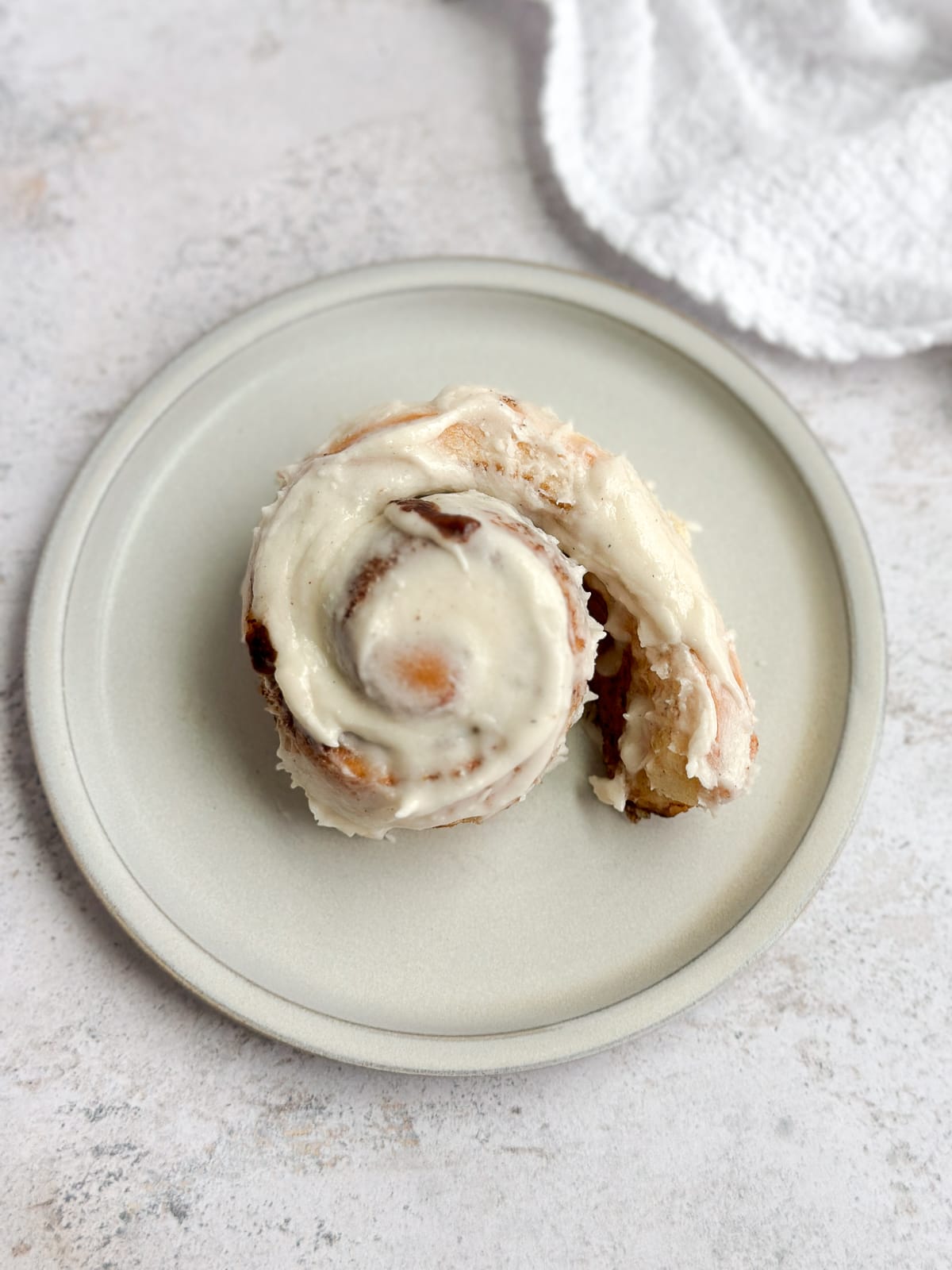 a single small batch cinnamon roll being unrolled on a plate.