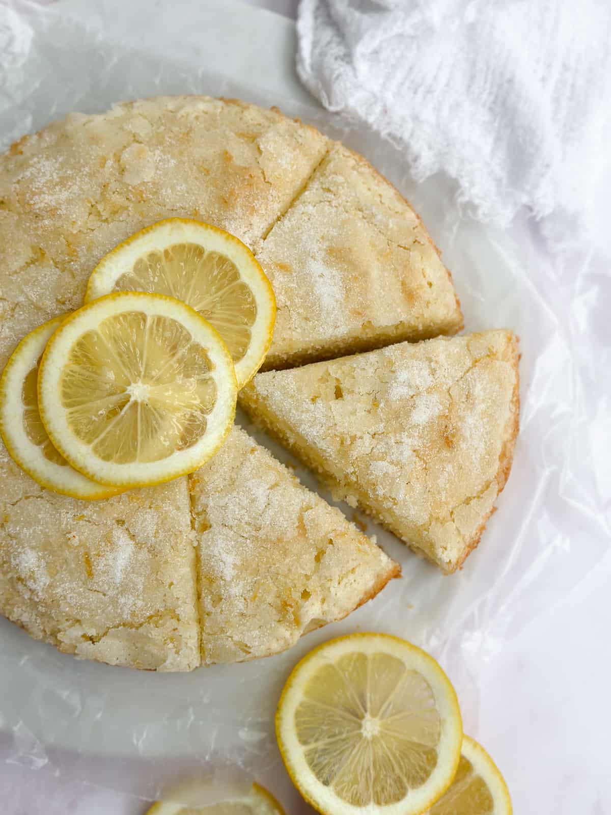 The whole lemon cake with some slices cut.