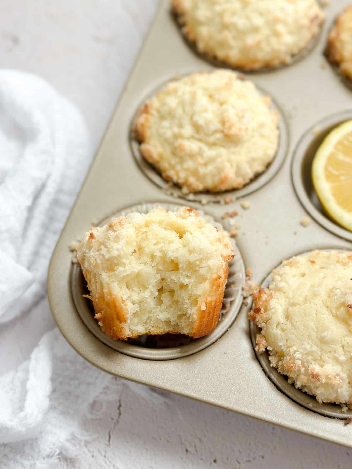 un gros plan d'un muffin au citron et à la noix de coco avec une bouchée manquante pour voir l'intérieur.