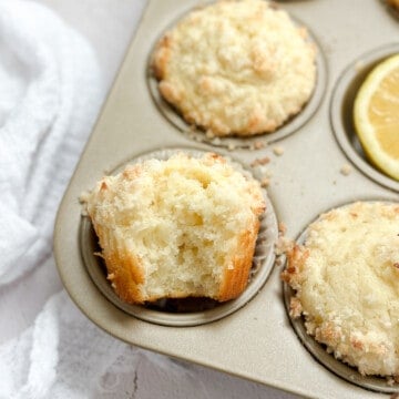 a close up of a coconut lemon muffin with a bite missing to see inside.