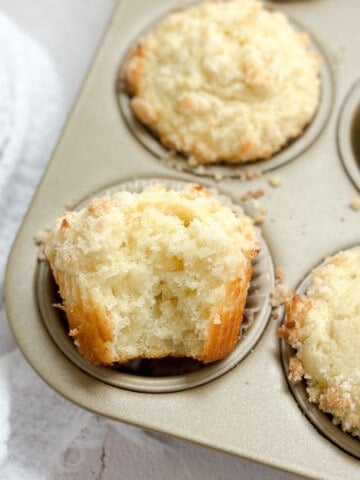 a close up of a coconut lemon muffin with a bite missing to see inside.