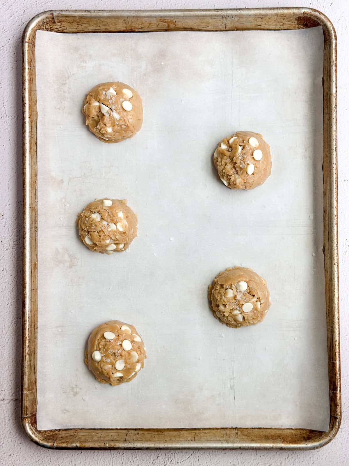 5 cookies balls on a baking sheet before baking.