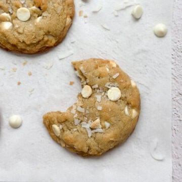 a coconut white chocolate cookie with a bite missing.