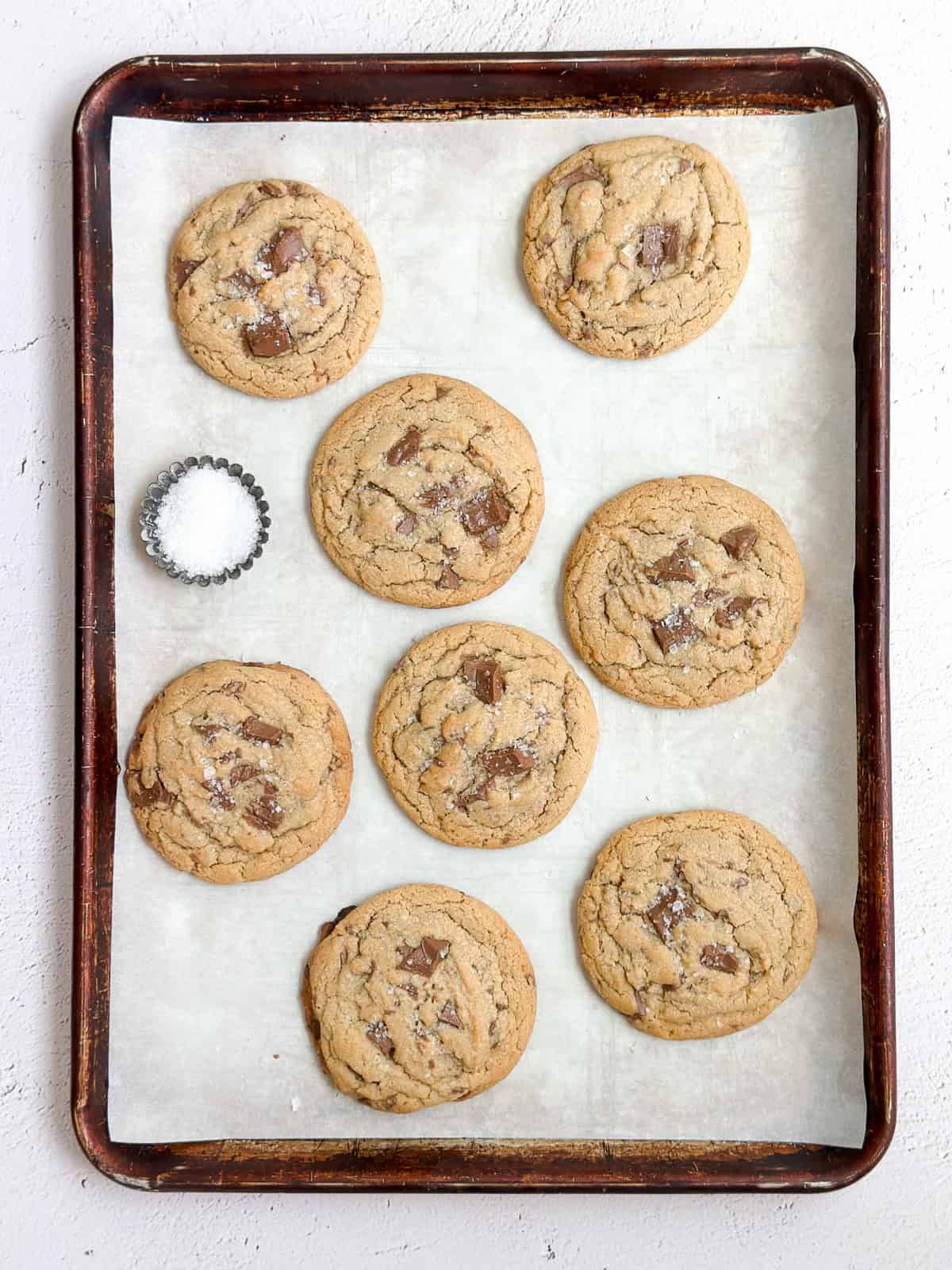 a cookie sheet full of cookies and some flaked salt.