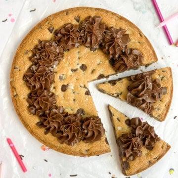 chocolate chip cookie cake with two slices cut into it.