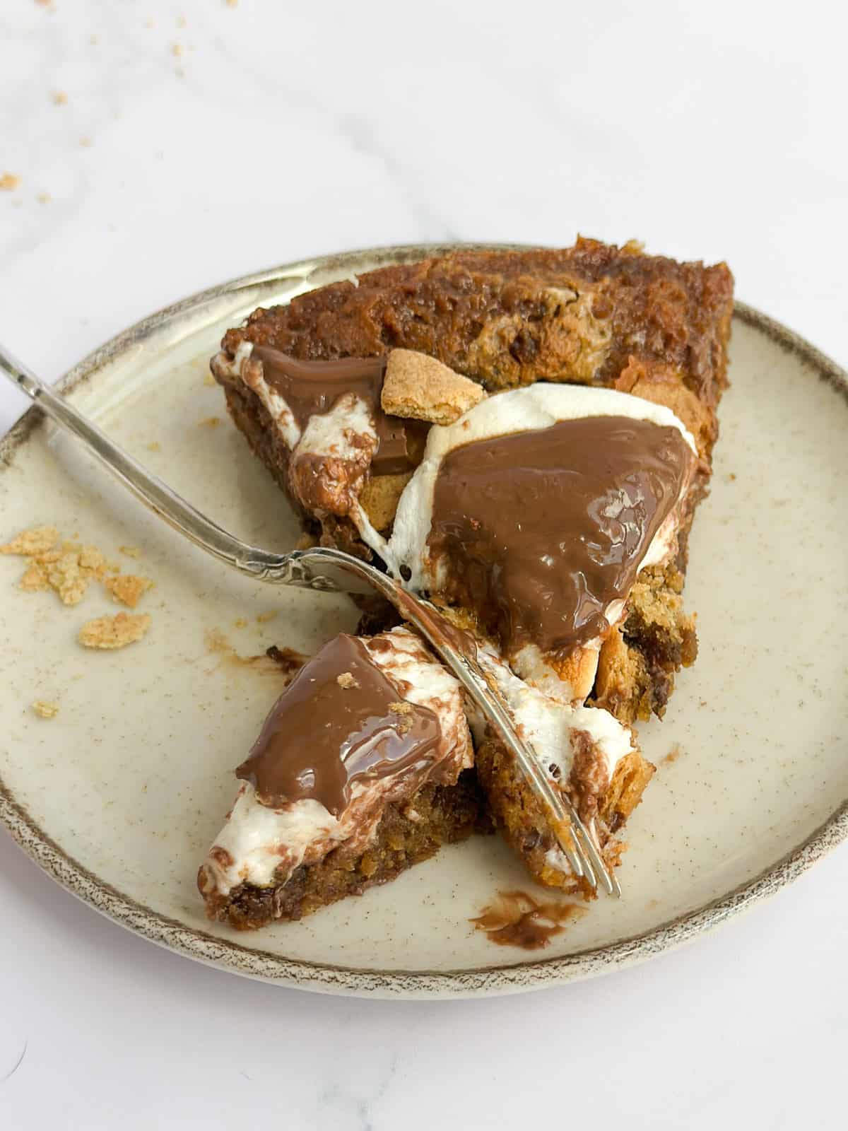 a slice of the s'mores cookie cake with a fork cutting into it.