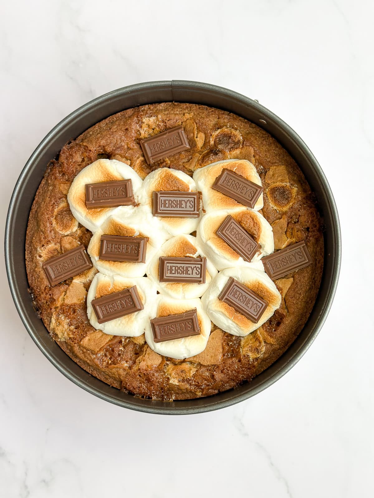 adding large marshmallows and chocolate to the top to broil.
