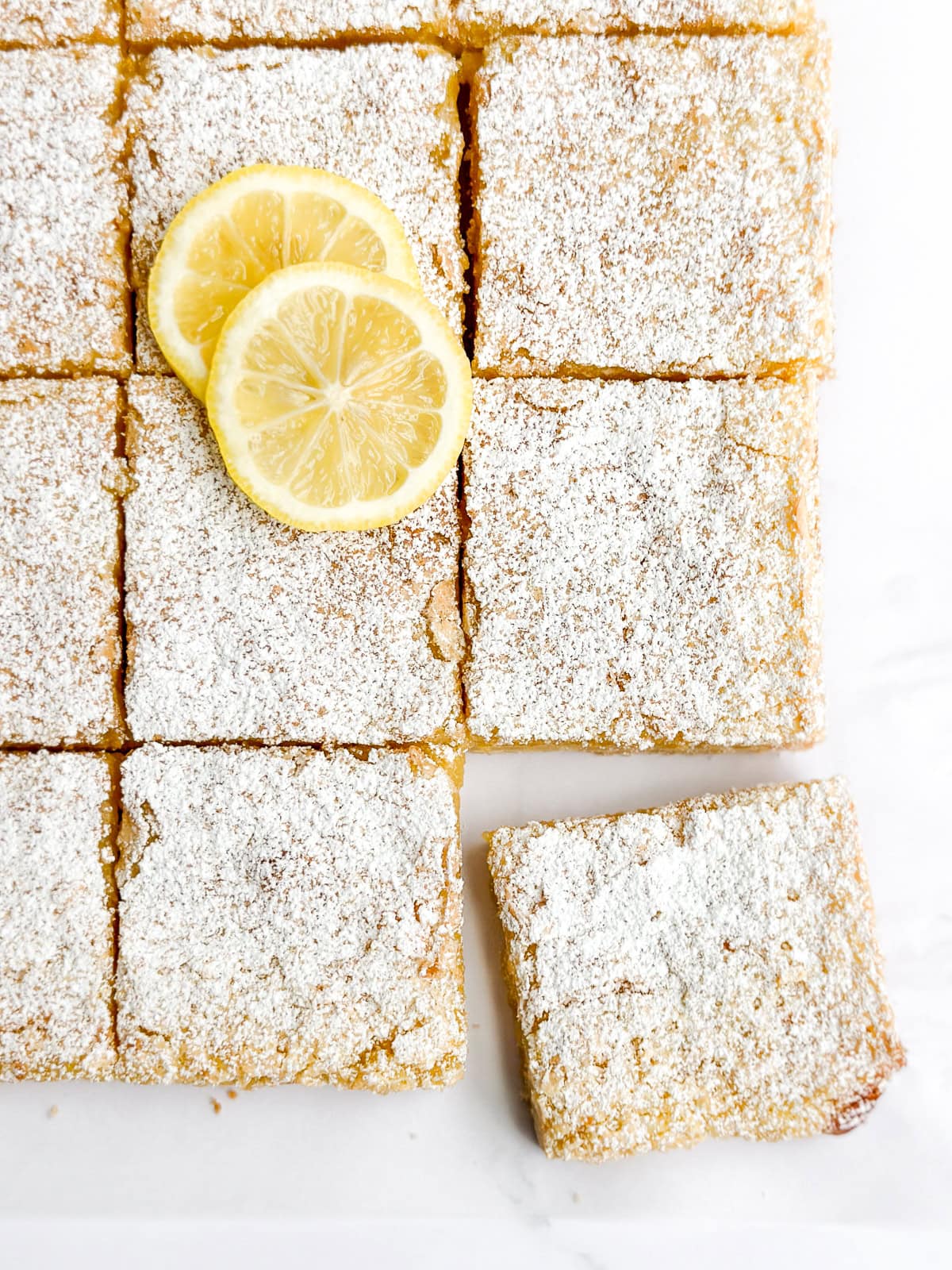 the lemon bars cut into squares with some lemon slices on top.