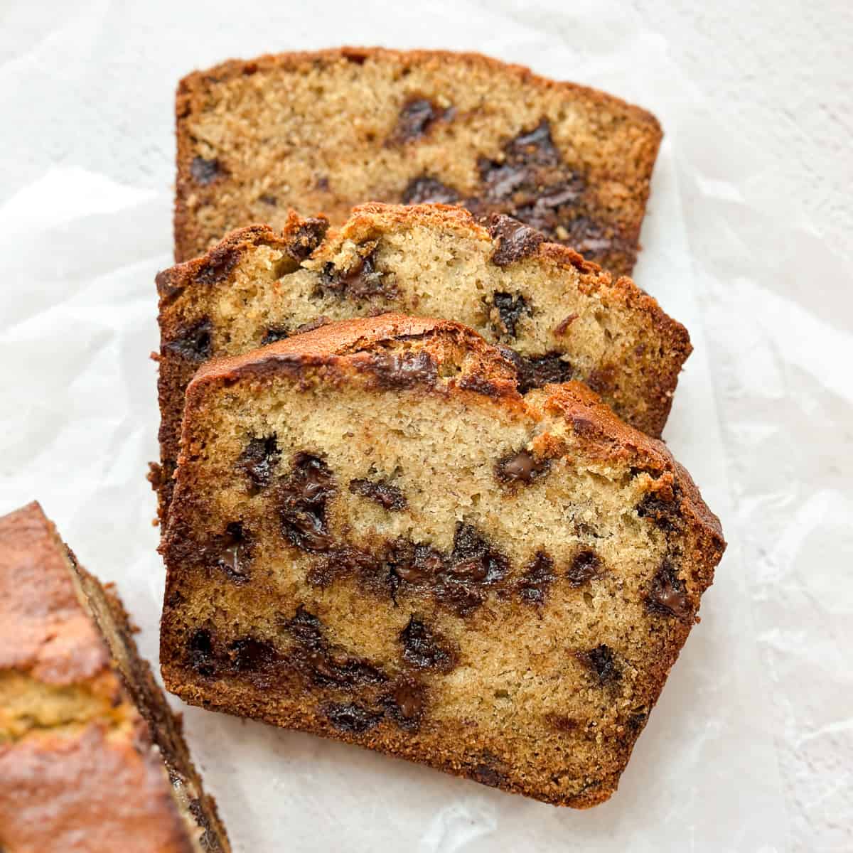three slices of browned butter banana chocolate chip bread stacked on top of each other.