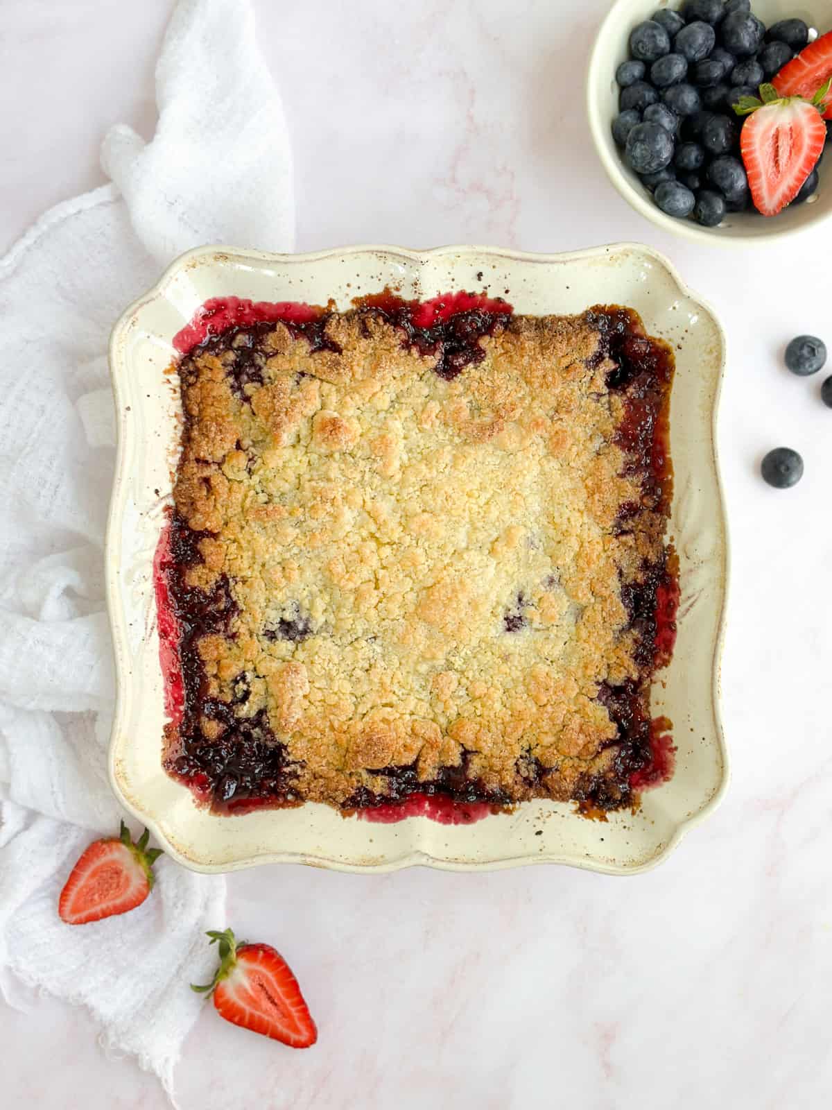 the whole mixed berry cobbler with some berries around it.