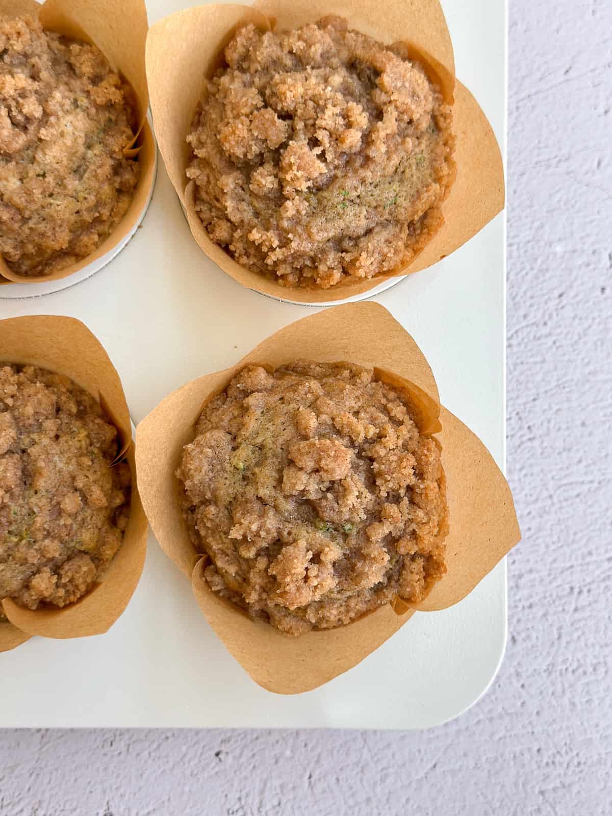a closeup of a few cinnamon zucchini crumb muffins still in the baking tin.
