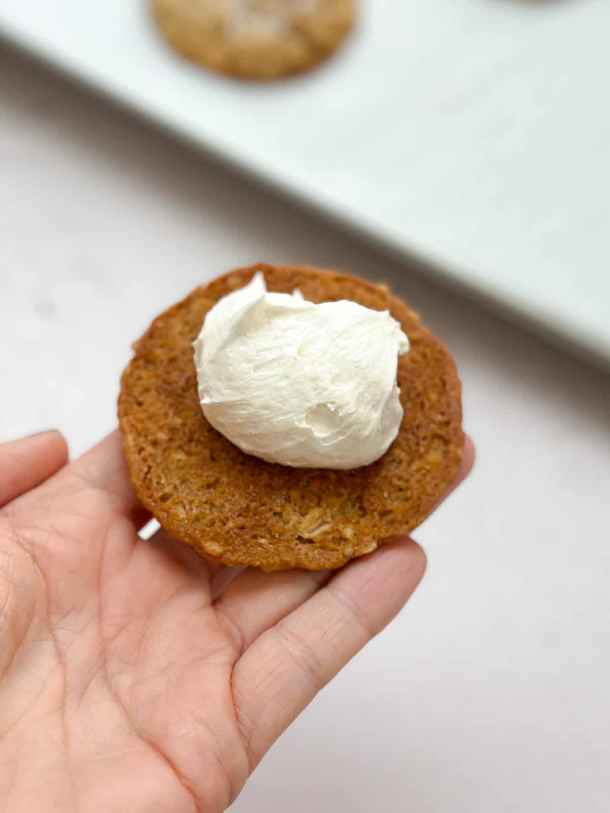topping an oatmeal cream pie cookie with frosting.