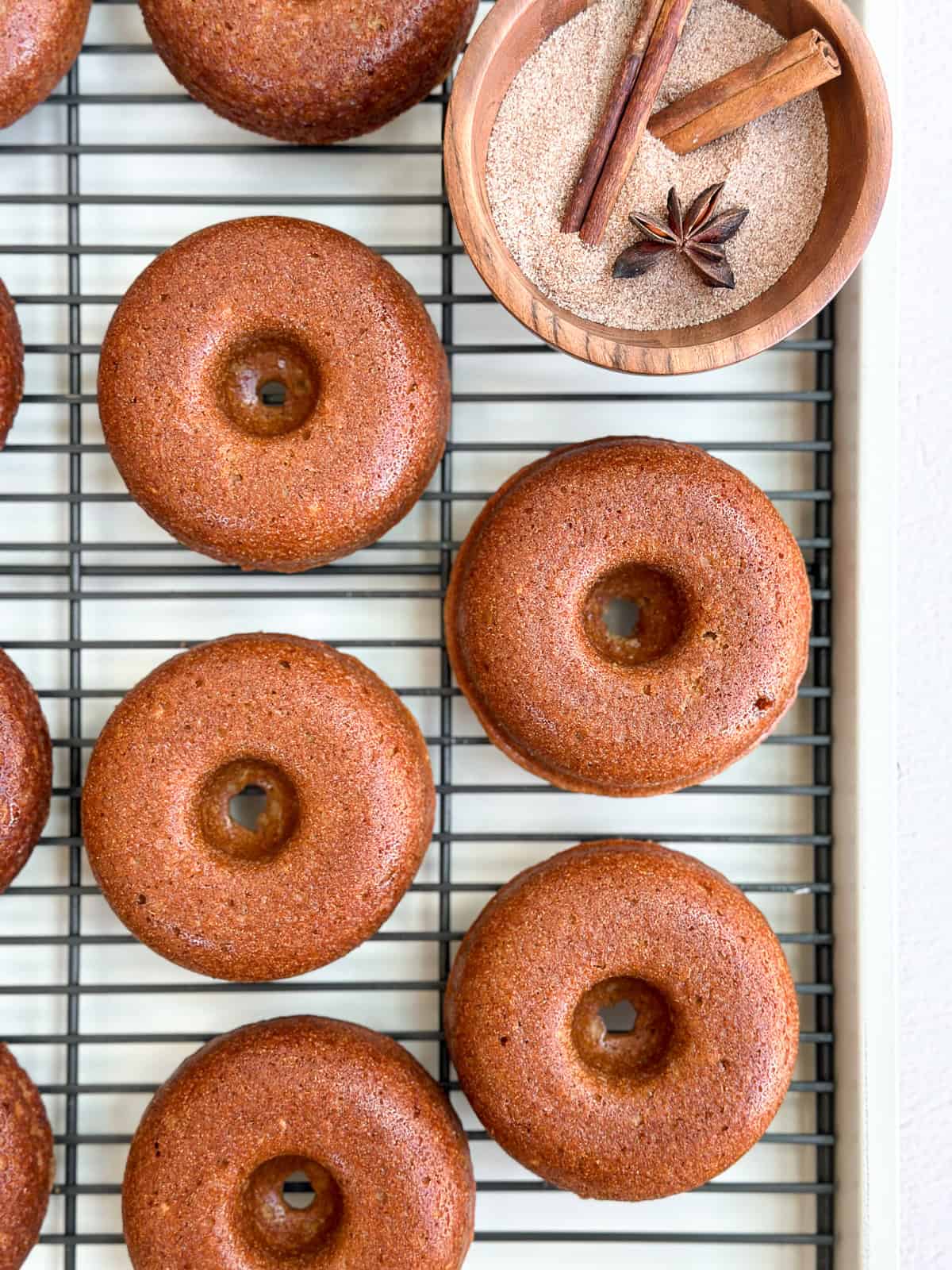 apple cider donuts on a cooling rack after baking.