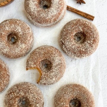 a few baked apple cider donuts with a bite missing from one.