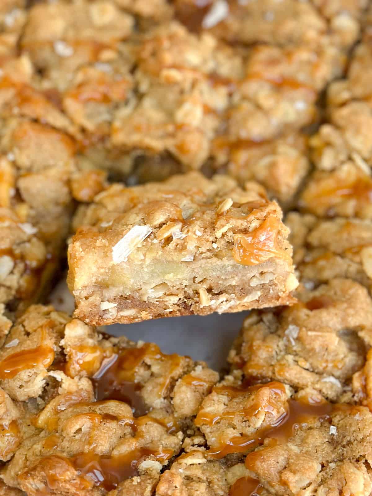 a salted caramel apple pie bar turned to the side to see the layers inside.