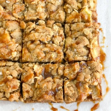 a close up of salted caramel apple pie bars with an extra caramel drizzle.