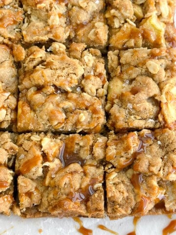 a close up of salted caramel apple pie bars with an extra caramel drizzle.