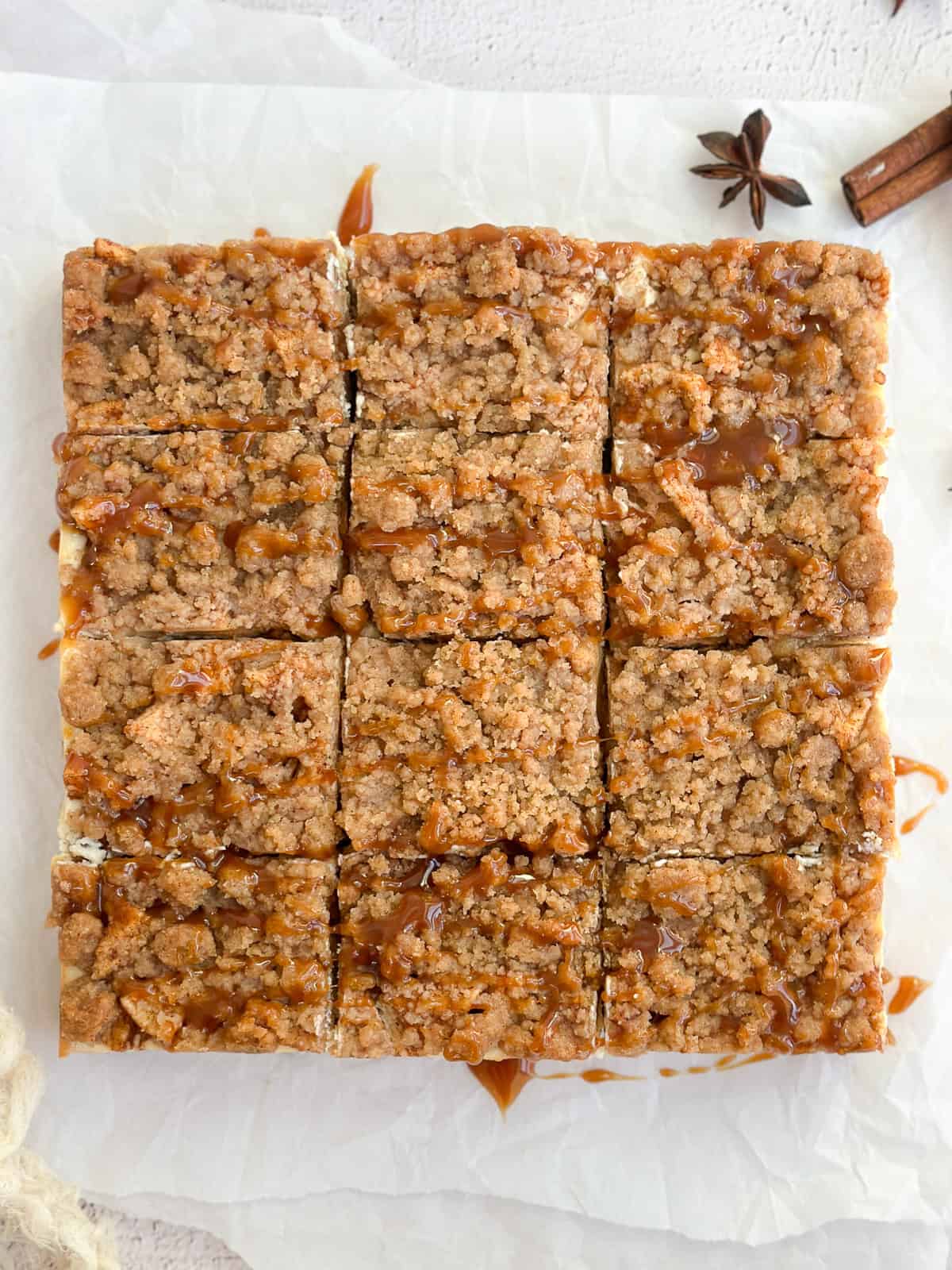 apple crumble cheesecake bars drizzled with caramel sauce and cut into squares.