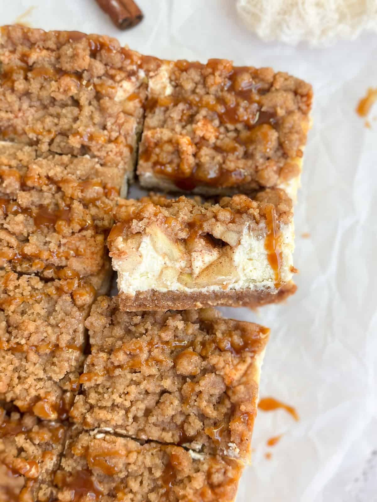 a close up of apple crumble cheesecake bars with one on it's side.