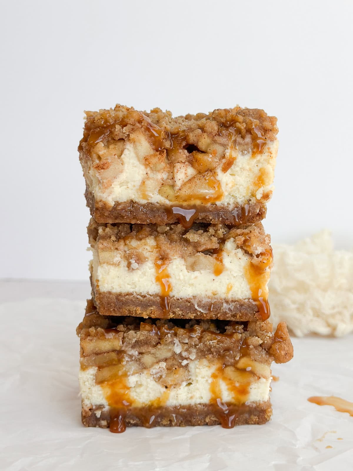 3 cheesecake bars stacked on top of each other with caramel sauce drizzled down the side.