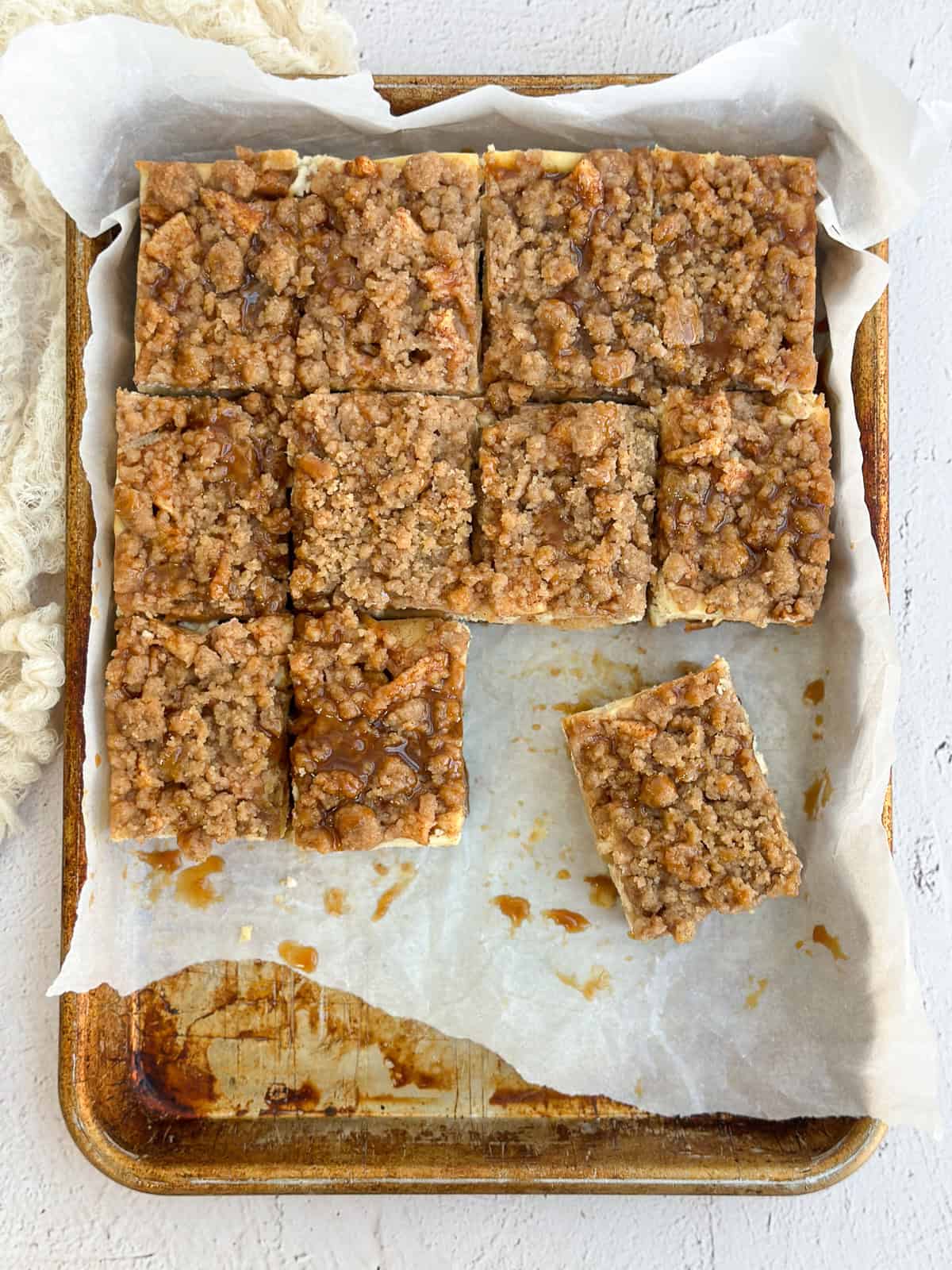 all the apple crumble cheesecake bars cut and placed on a baking sheet.