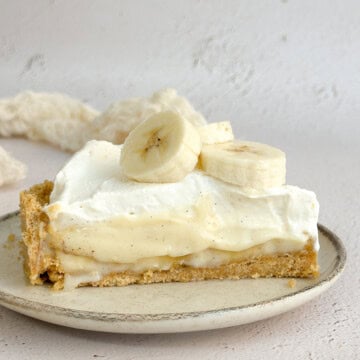 a slice of banana cream pie with graham cracker crust on a plate.