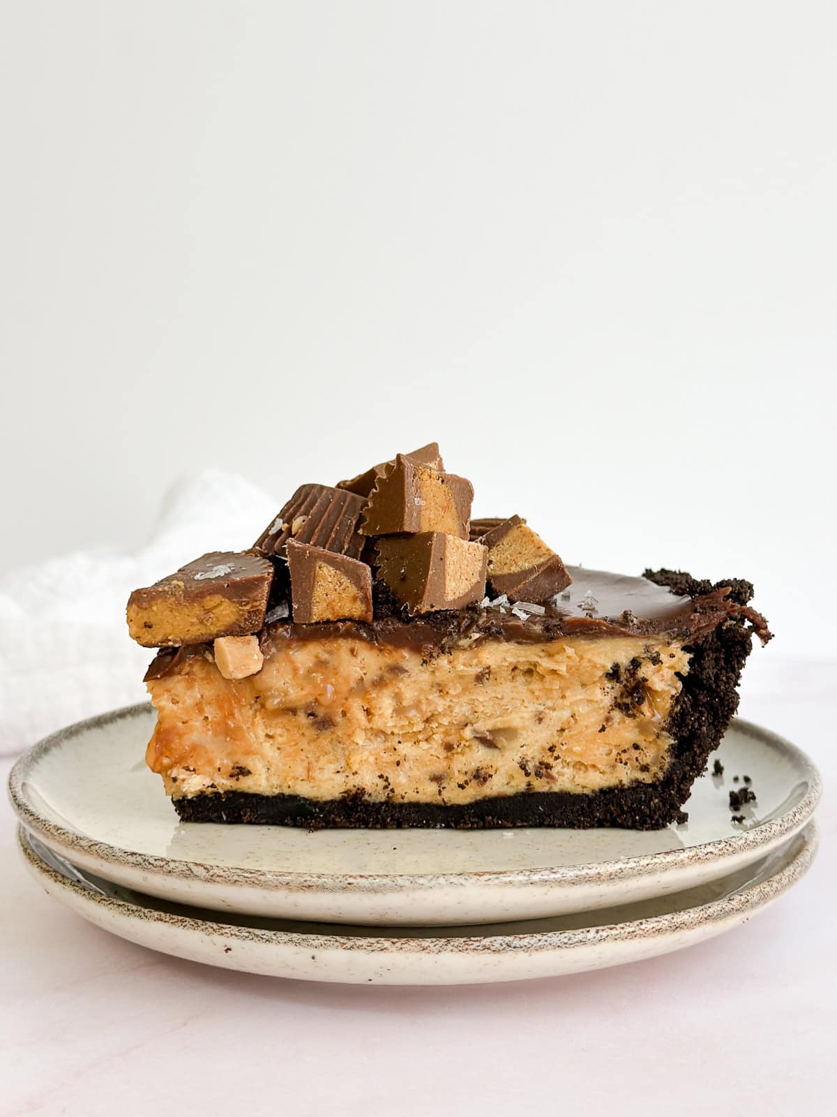 a whole slice of peanut butter pie with chocolate ganache on a plate topped with reese's pb cups.