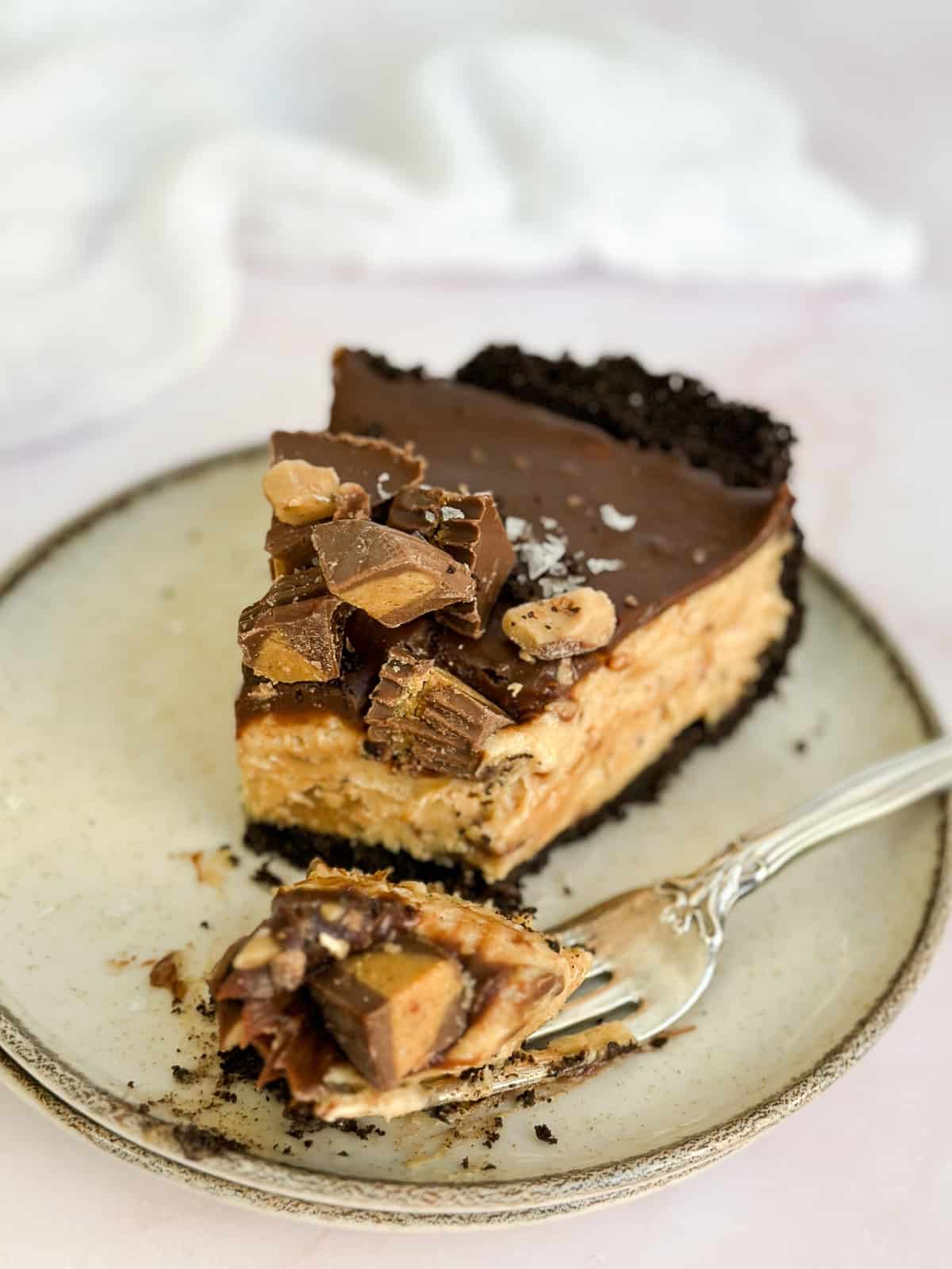 a bite missing from a slice of peanut butter pie with chocolate ganache on top.