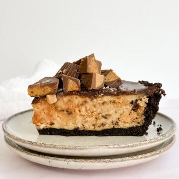 a whole slice of peanut butter pie with chocolate ganache on a plate topped with reese's pb cups.
