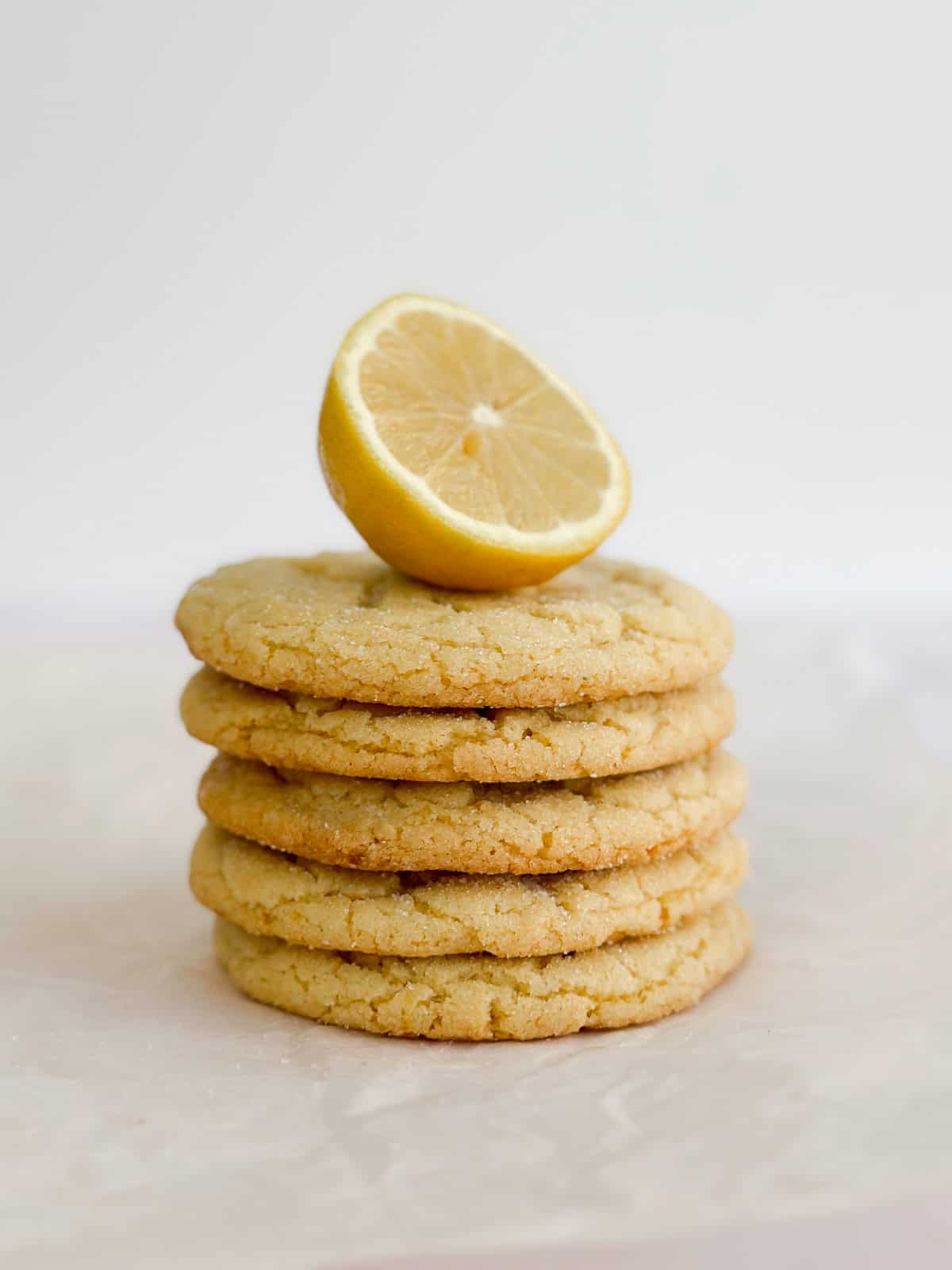 all 5 cookies stacked on top of each other with a lemon on top.