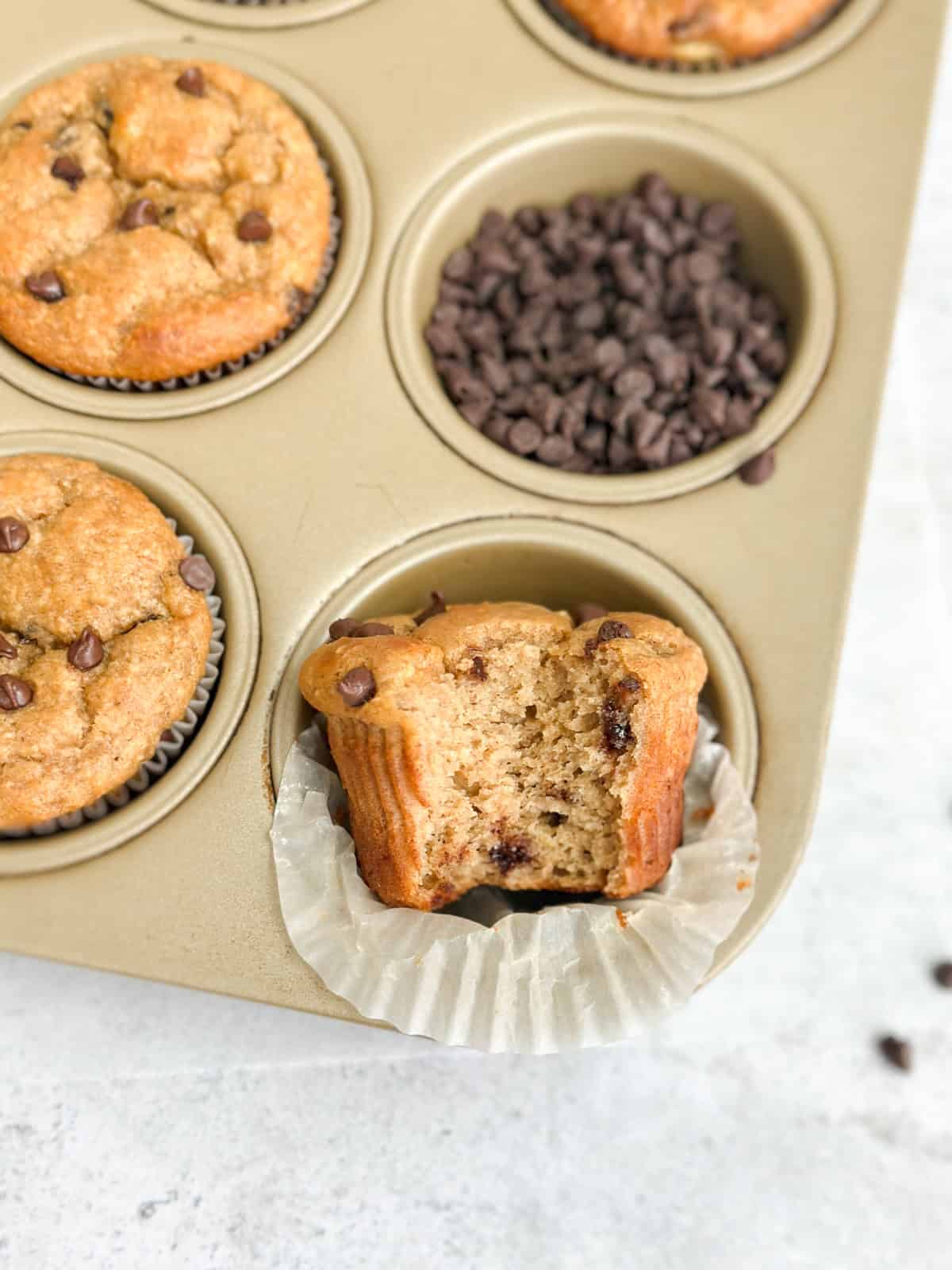 one banana chocolate chip protein muffin with a bite missing to see the inside texture.