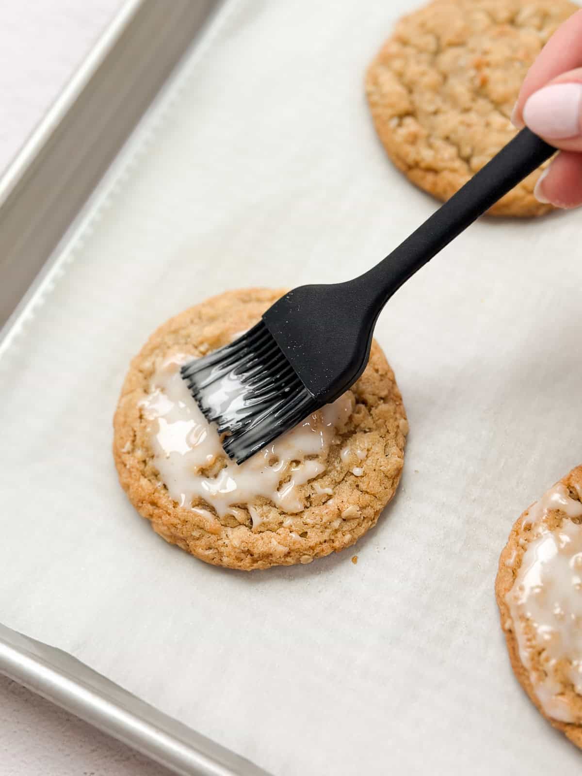 an oatmeal cookie being brushed with icing.