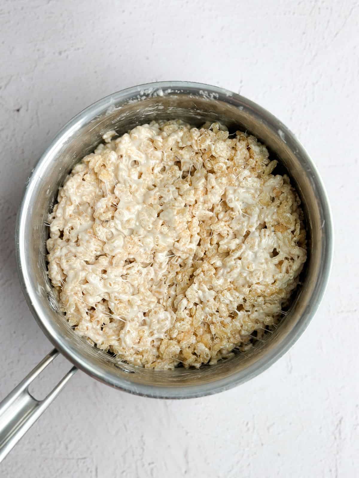 rice krispie cereal being stirred in to the marshmallows.