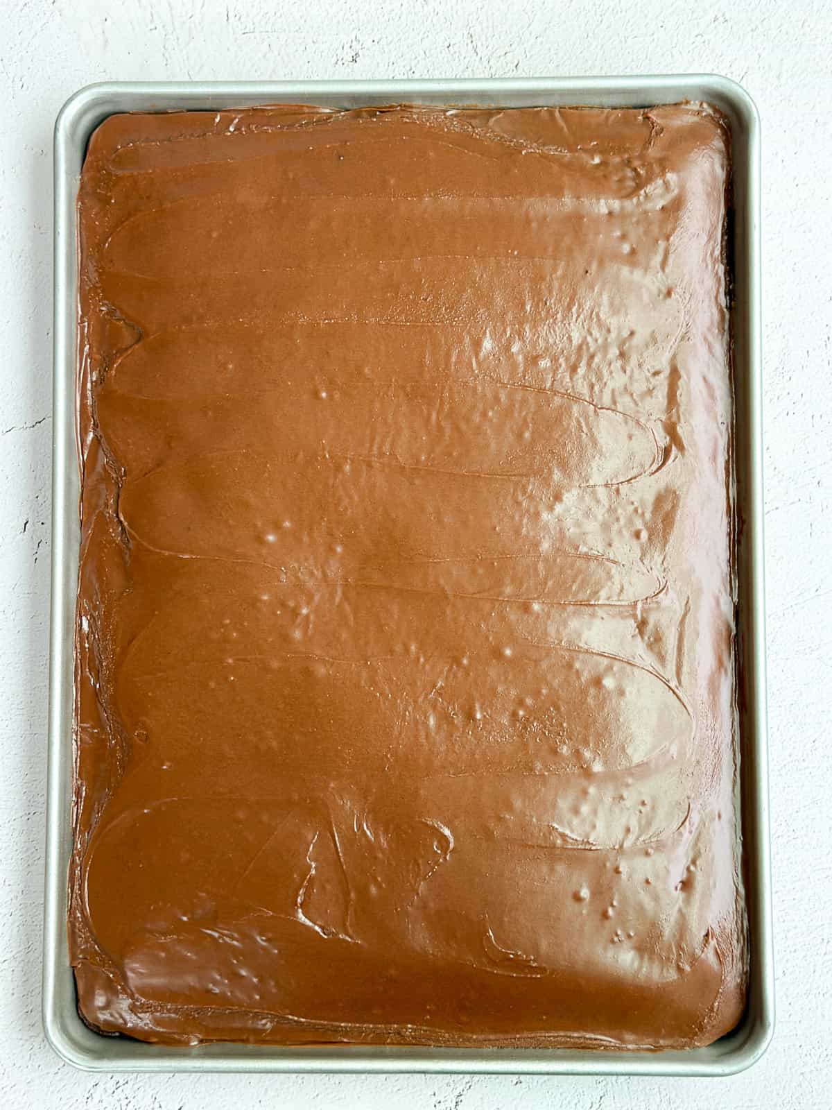 the frosting poured onto the warm sheet cake.