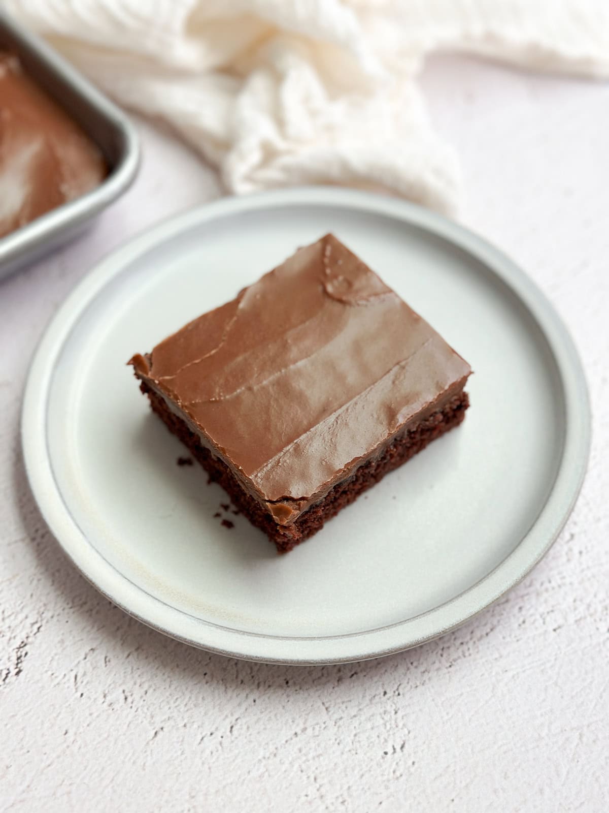 a single slice of cake on plate with the whole cake behind it.