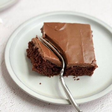a single piece of chocolate buttermilk texas sheet cake on a plate with a fork through it.