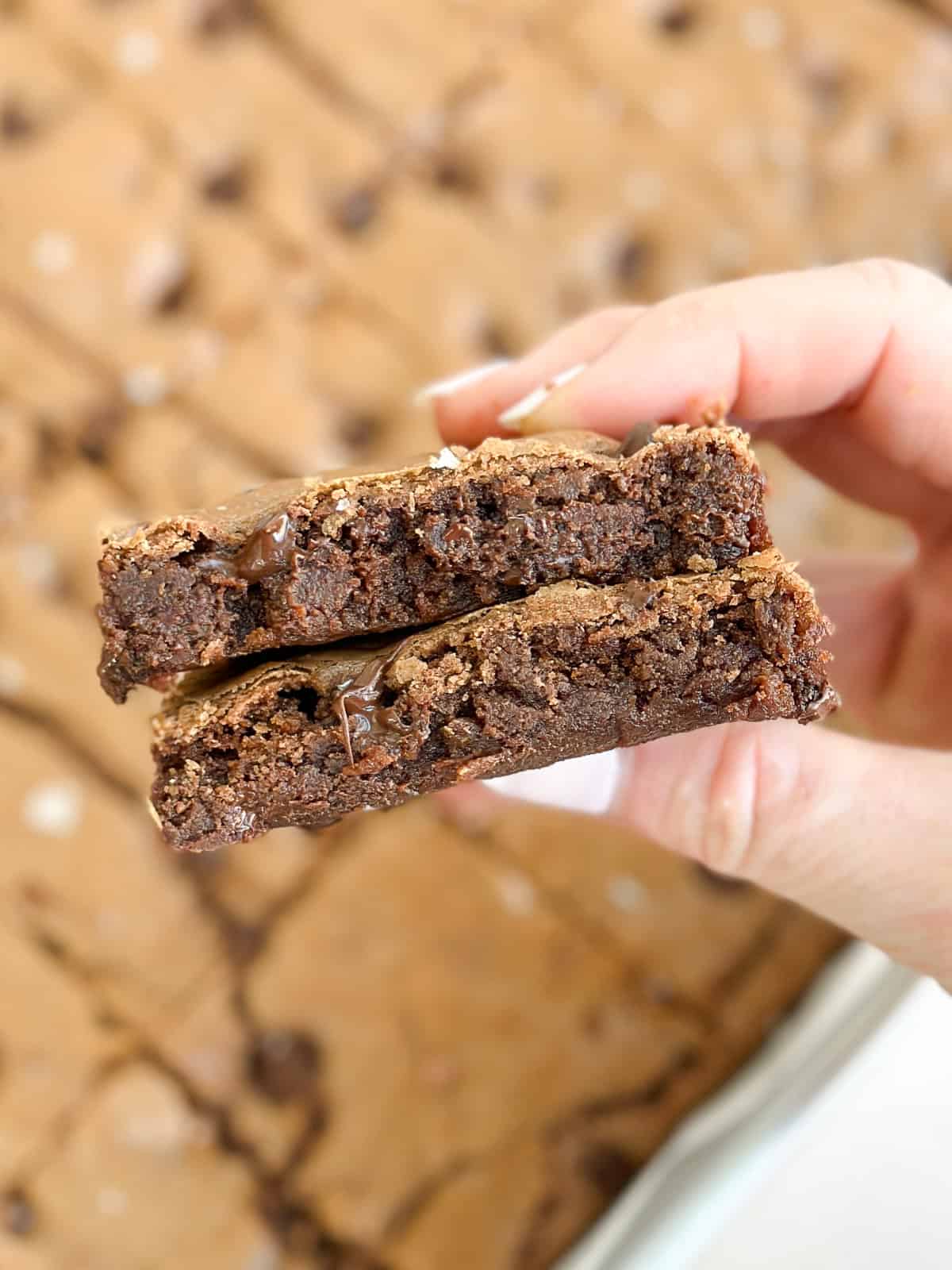 my hand holding 2 stacked brownies to see the inside texture.