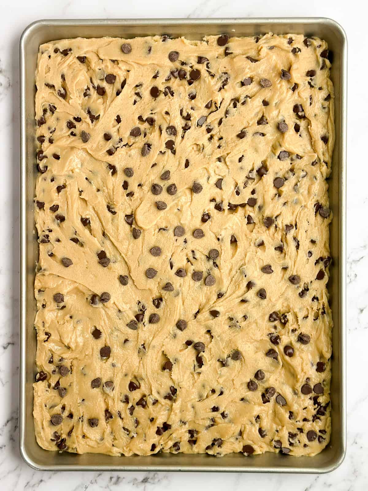 chocolate chip cookie dough spread into the sheet pan.