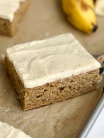a close up of a single slice of the brown butter banana sheet cake on a sheet cake pan.