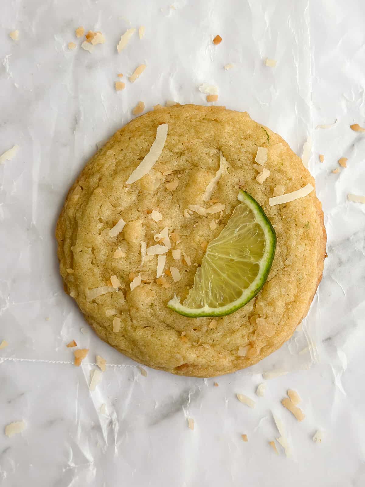 Gros plan d'un biscuit à la noix de coco et au citron vert avec une tranche de citron vert sur le dessus.