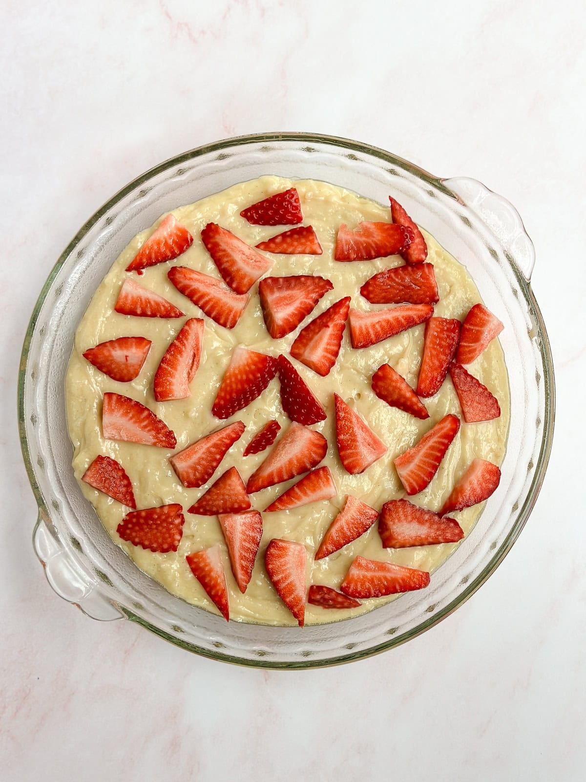 batter added to the cake pan and strawberries topped.