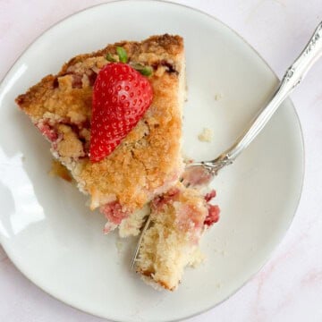 a slice of coconut strawberry cake on a plate with a fork holding a bite.